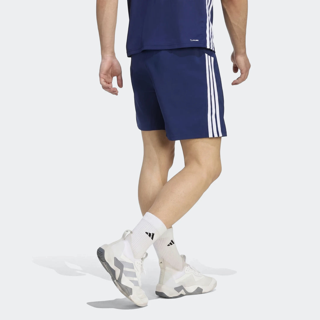 Men's navy blue Adidas Workout Essentials Base 3-Stripes Woven Shorts, shown from the side, worn with white socks and