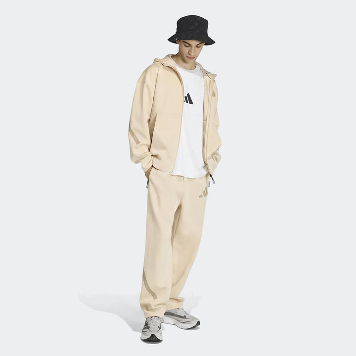 Men's beige Z.N.E. full-zip hoodie and matching sweatpants set, worn by a model with a black bucket hat and sneakers.
