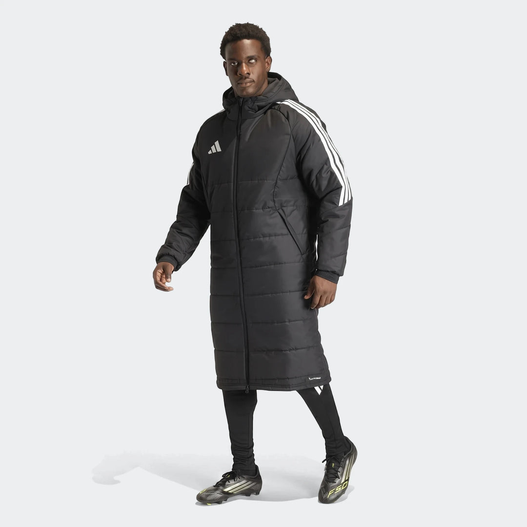 Men's black Adidas Tiro 26 padded long coat worn by an athletic male model, featuring white 3-stripes on sleeves and chest