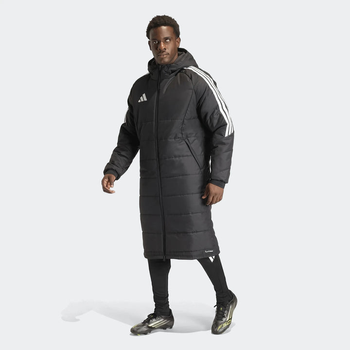 Men's black Adidas Tiro 26 padded long coat worn by an athletic male model, featuring white 3-stripes on sleeves and chest