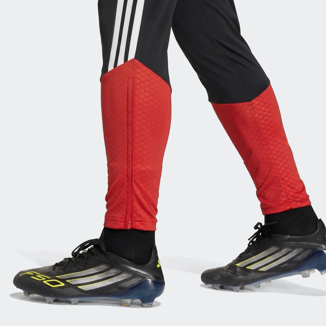 Men's black and red Adidas Germany training pants with black F50 soccer cleats on cropped legs.