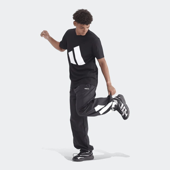Men's black Sportswear Badge Of Sport T-Shirt and matching track pants with white accents, worn by a model in a dynamic