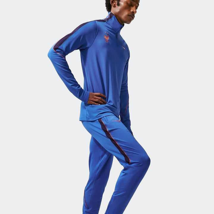Men's blue Nike FFF Strike Dri-Fit soccer knit tracksuit with matching quarter-zip top and track pants, side view.