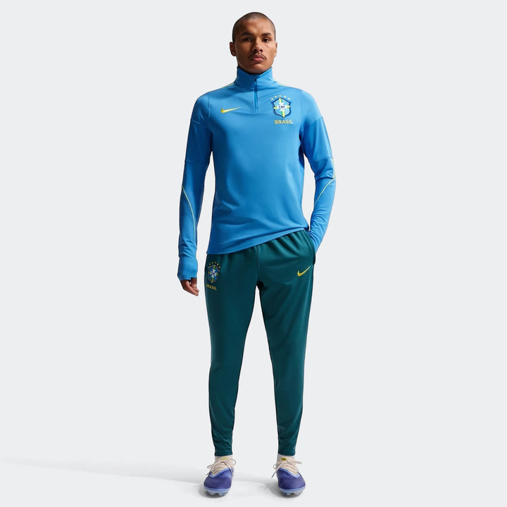 Men's Brazil Strike Nike Dri-FIT soccer training kit, featuring a blue quarter-zip top and green knit pants.