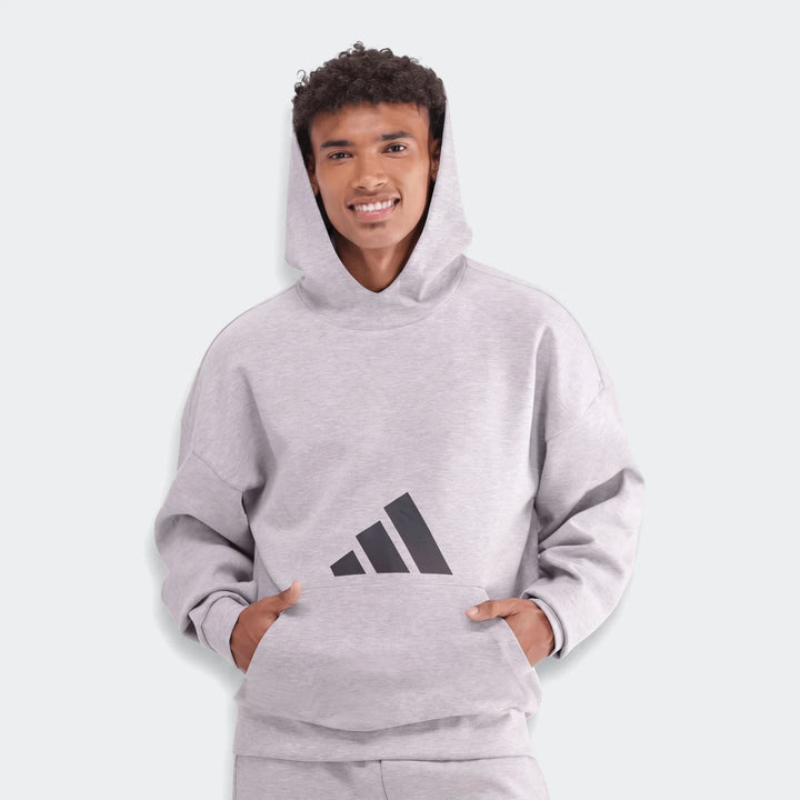 Men's grey oversized Adidas Future Icons 3-Bar Hoodie, featuring the iconic black logo, worn by a smiling model.