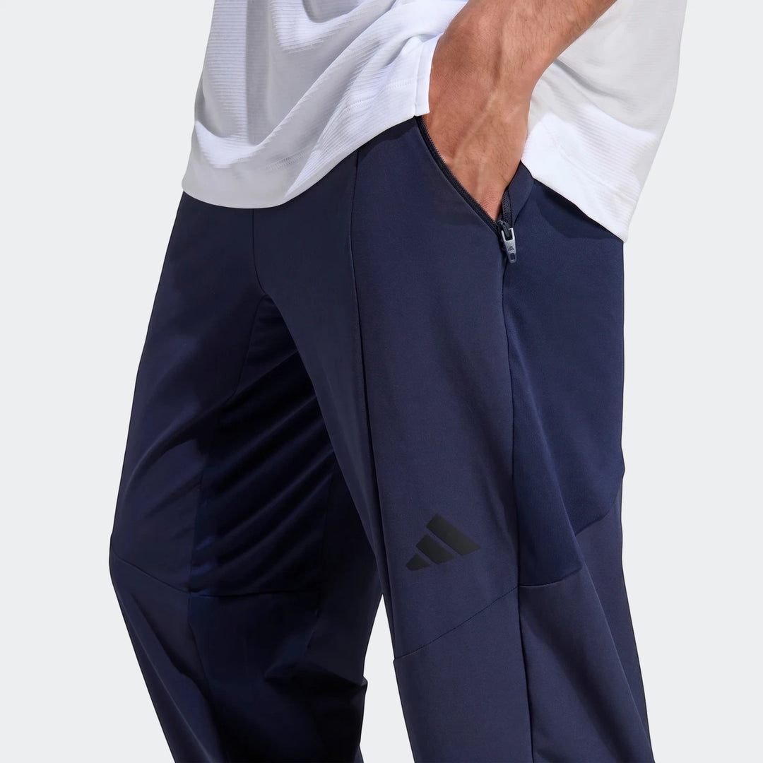 Close-up of men's navy blue Adidas D4T Hybrid Pants with a zippered pocket and Adidas logo, worn by a model.