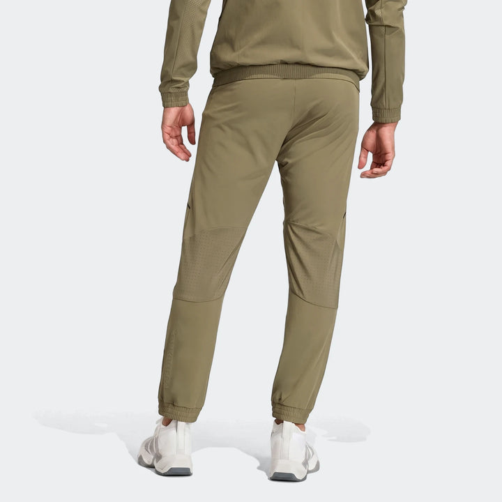 Back view of men's technical apparel slim pants in olive green with perforated details, paired with a matching jacket and