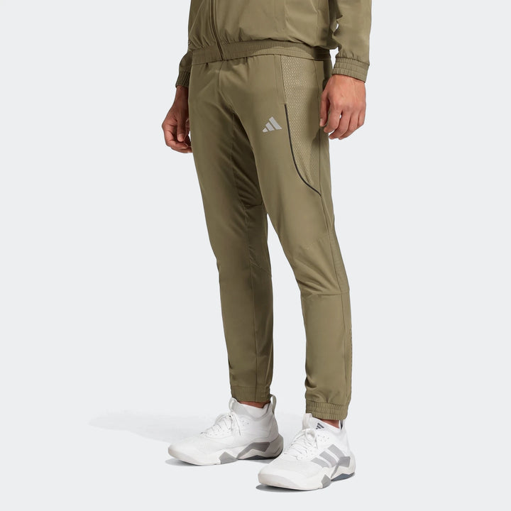 Olive green men's Technical Apparel Slim Pants, featuring textured panels and Adidas branding, styled with white sneakers.