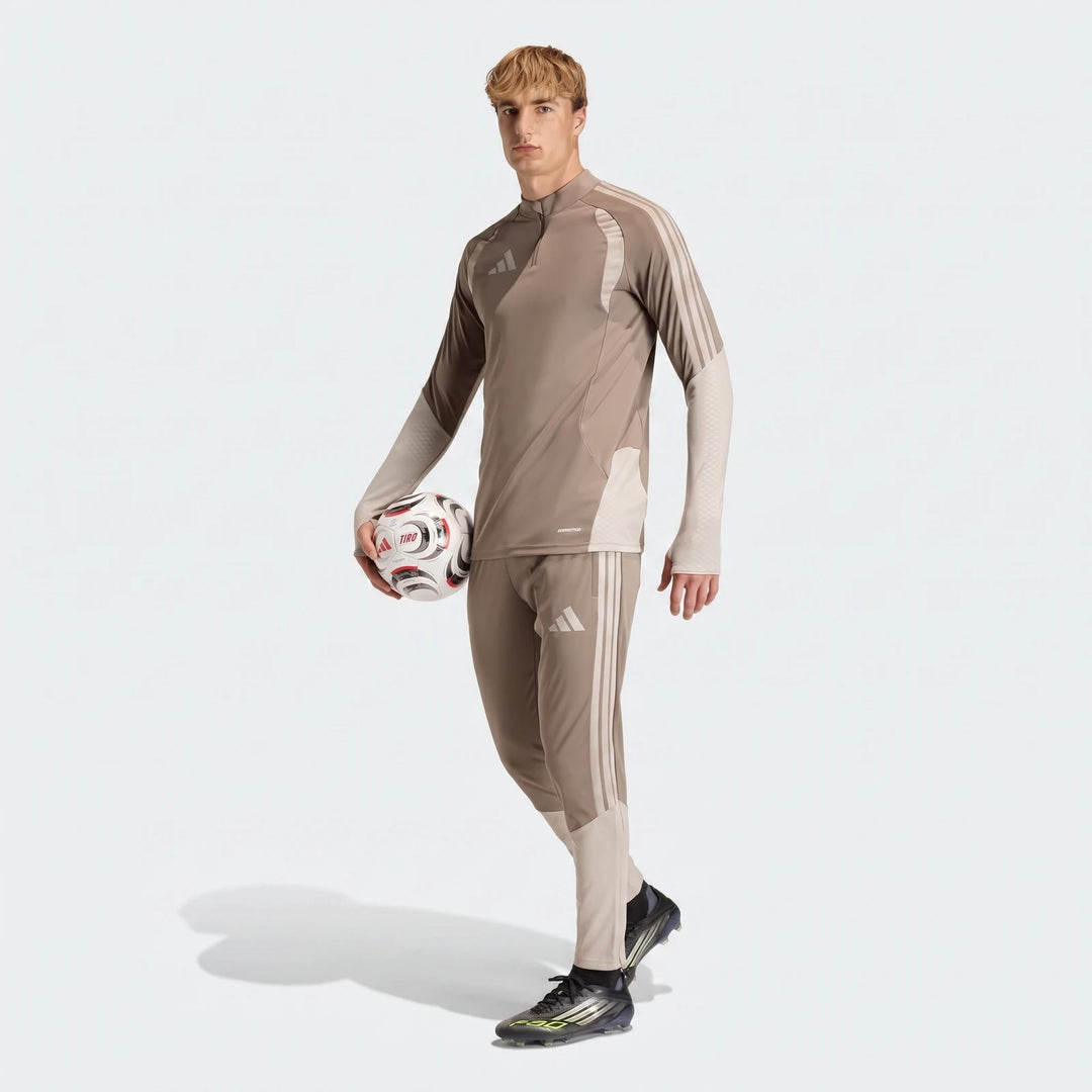 Men's Tior26C brown athletic pants and matching long-sleeve top on a model holding a soccer ball.