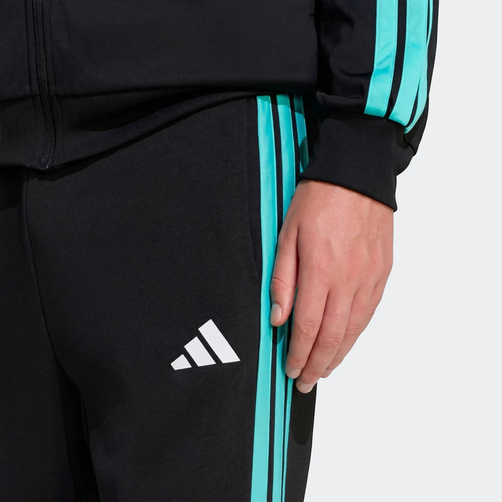 Close-up of black Mercedes-Amg Petronas Formula 1 Team Dna Pants with teal side stripes and white Adidas logo, worn by a