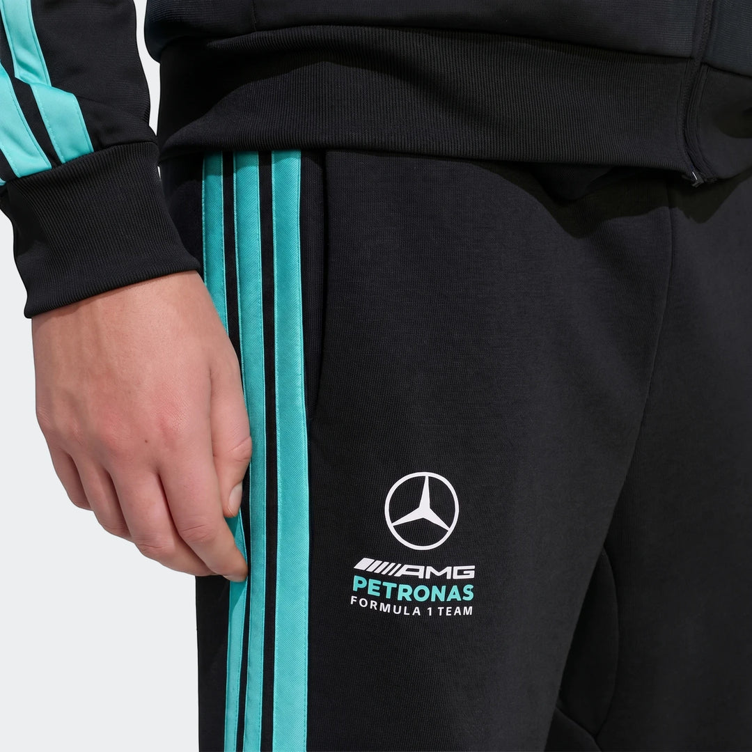 Close-up of black Mercedes-AMG Petronas Formula 1 Team DNA Pants worn by a model, featuring teal stripes and white team logo.