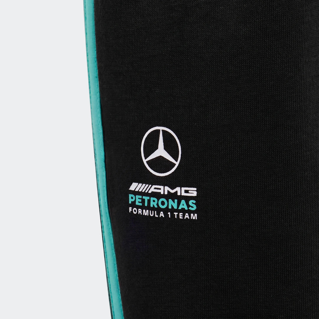 Close-up of Mercedes-AMG Petronas Formula 1 Team DNA black pants for kids, featuring a turquoise side stripe and team logo.