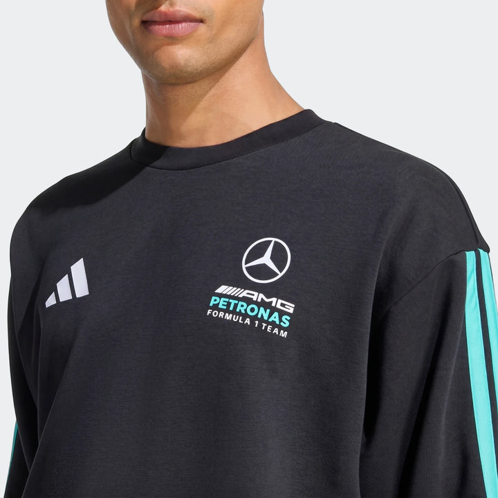 Close-up of a model wearing a black Mercedes-AMG Petronas Formula 1 Team Dna Sweatshirt with logos and teal stripes.