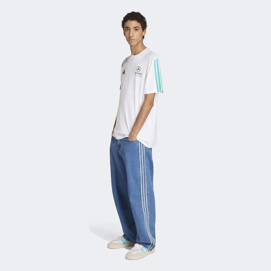 Male model wearing a white Mercedes-AMG Petronas Formula 1 Team DNA T-shirt, blue striped jeans, and white sneakers, full