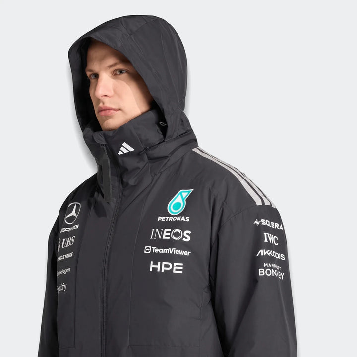 Close-up of a male model wearing a black Mercedes-Amg Petronas Formula 1 Team Energy jacket with hood and sponsor logos.