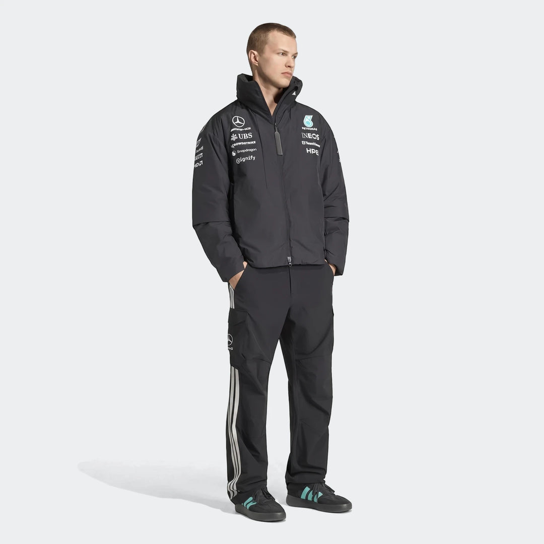 Male model wearing a dark gray Mercedes-Amg Petronas Formula 1 Team Energy Jacket and black pants, full body shot.