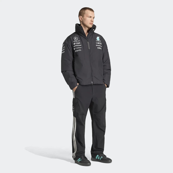 Male model wearing a dark gray Mercedes-Amg Petronas Formula 1 Team Energy Jacket and black pants, full body shot.