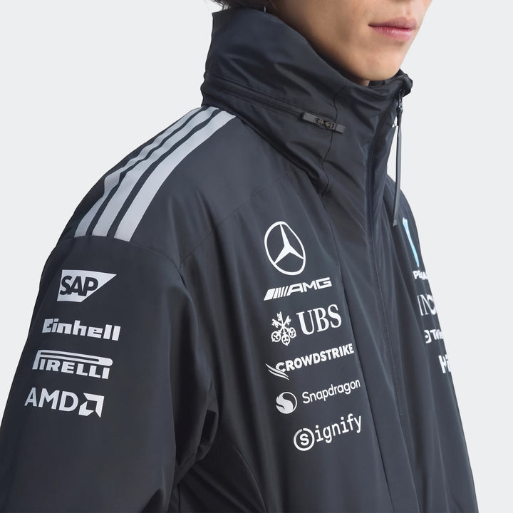 Close-up of a person wearing a dark Mercedes-AMG Petronas Formula 1 Team Energy Jacket with sponsor logos and grey shoulder