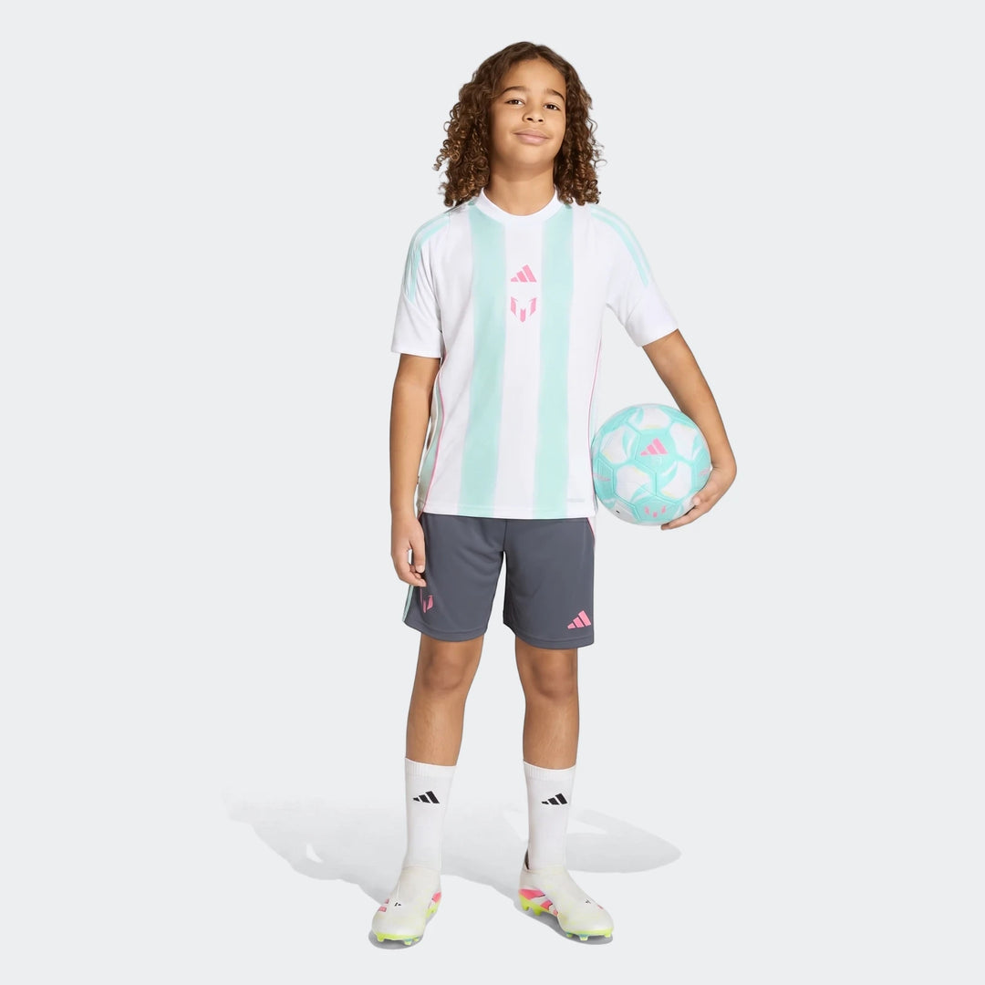 A young boy models the white, mint green, and pink Messi Training Jersey Youth with gray shorts and a soccer ball.