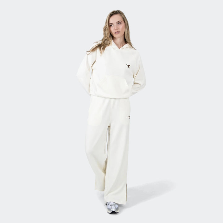 Woman wearing cream Michelle Hoodie and matching wide-leg pants with silver sneakers, posing against a white background.