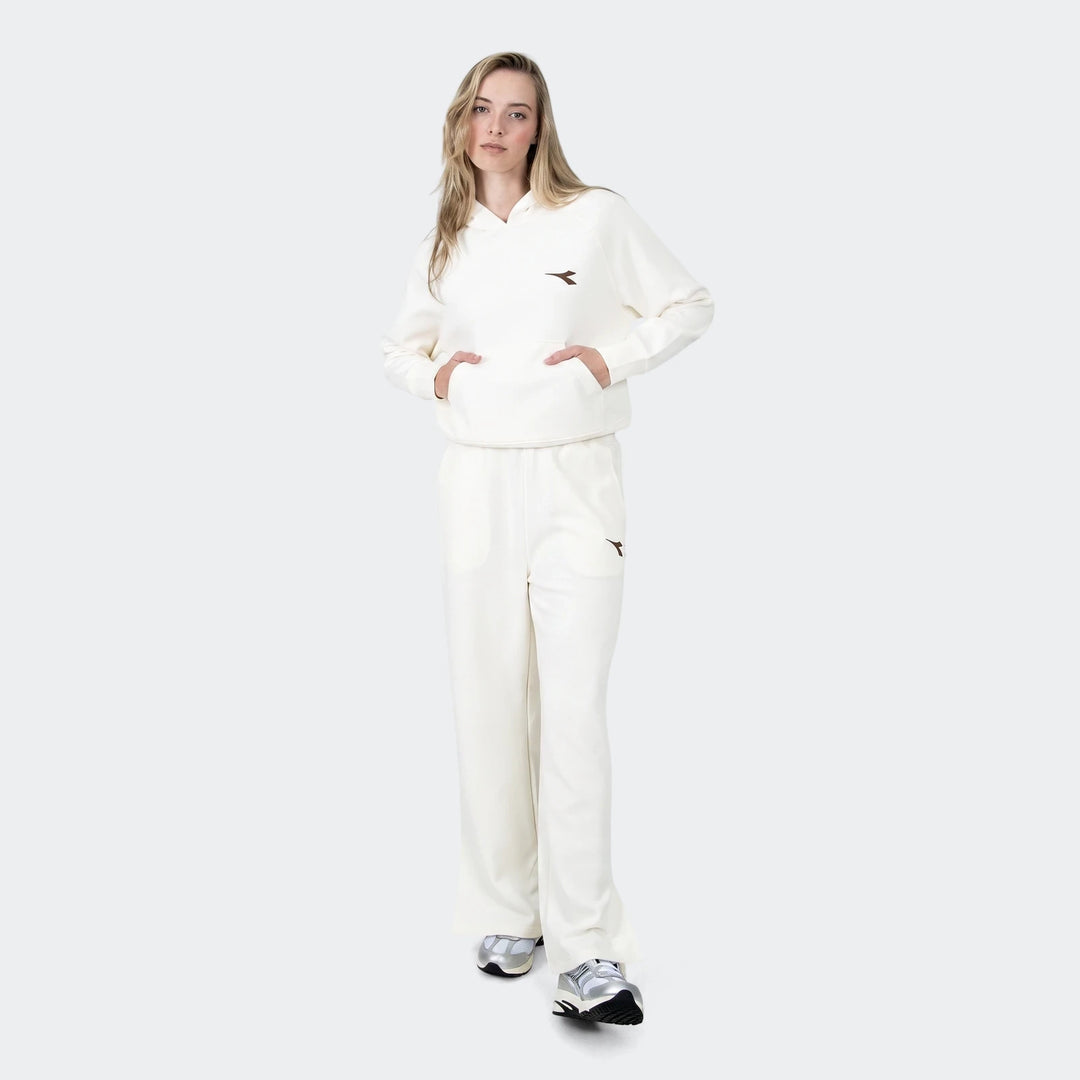 Full-body shot of a woman wearing an off-white Michelle hoodie and matching relaxed-fit sweatpants, paired with metallic