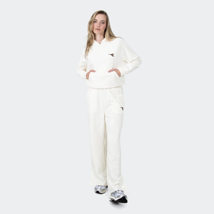 Full-body shot of a woman wearing an off-white Michelle hoodie and matching relaxed-fit sweatpants, paired with metallic