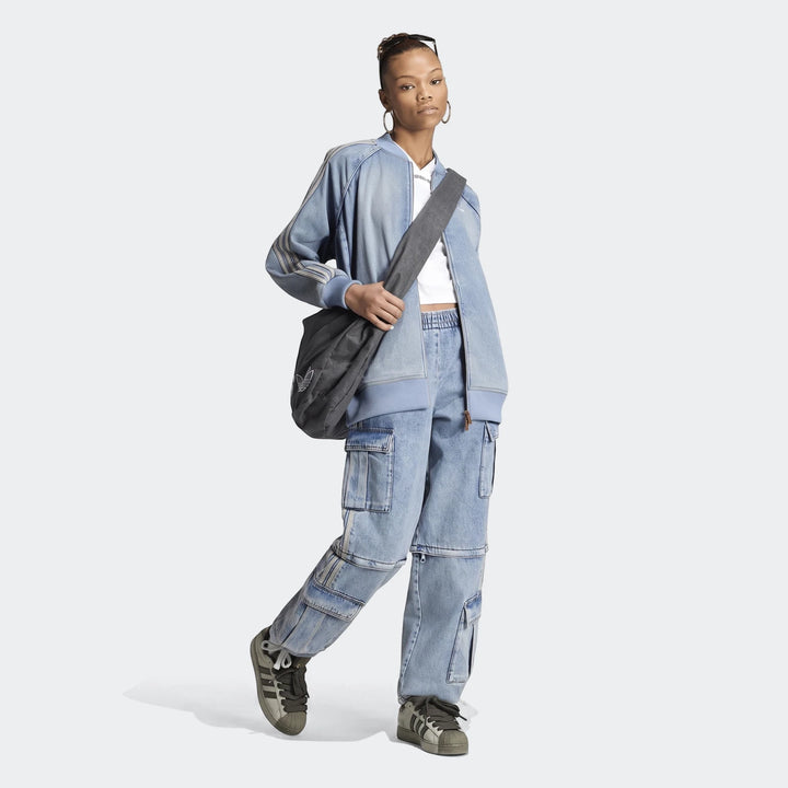 A woman wears a light blue denim bomber jacket, a white crop top, light blue mid-rise 2-in-1 denim cargo pants, grey