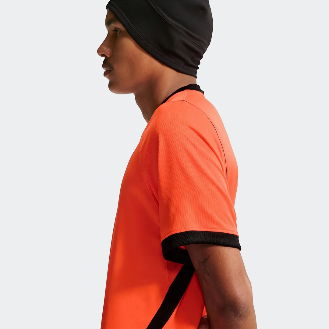 Profile view of a male model wearing the Netherlands National Team 2026 Stadium Home orange Nike Dri-Fit soccer jersey with