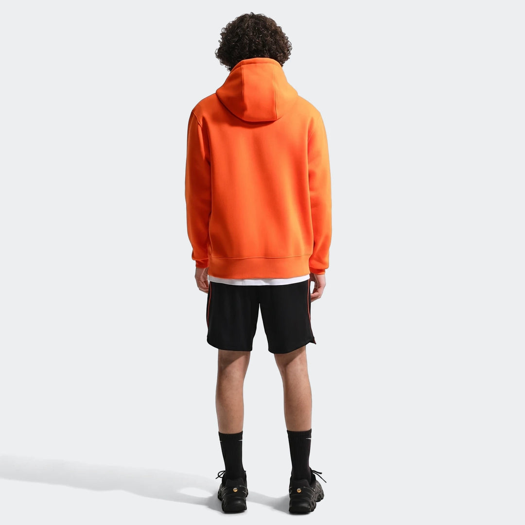 Men's Nike Netherlands Club orange soccer pullover hoodie, back view, worn with black shorts and sneakers.