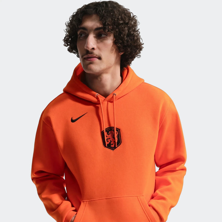 Close-up of a male model wearing the vibrant orange Netherlands Club Nike Soccer Pullover Hoodie with KNVB crest.