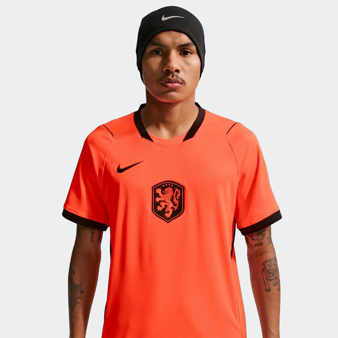 Male model wearing Netherlands National Team 2026 Stadium Home Orange Nike Dri-Fit Soccer Jersey with KNVB crest.
