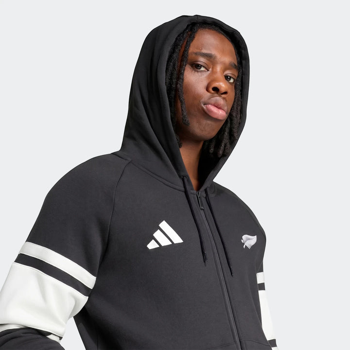 Close-up of a model wearing a black New Zealand Rugby Leisurewear Full Zip Hoodie with white stripes and team logos.