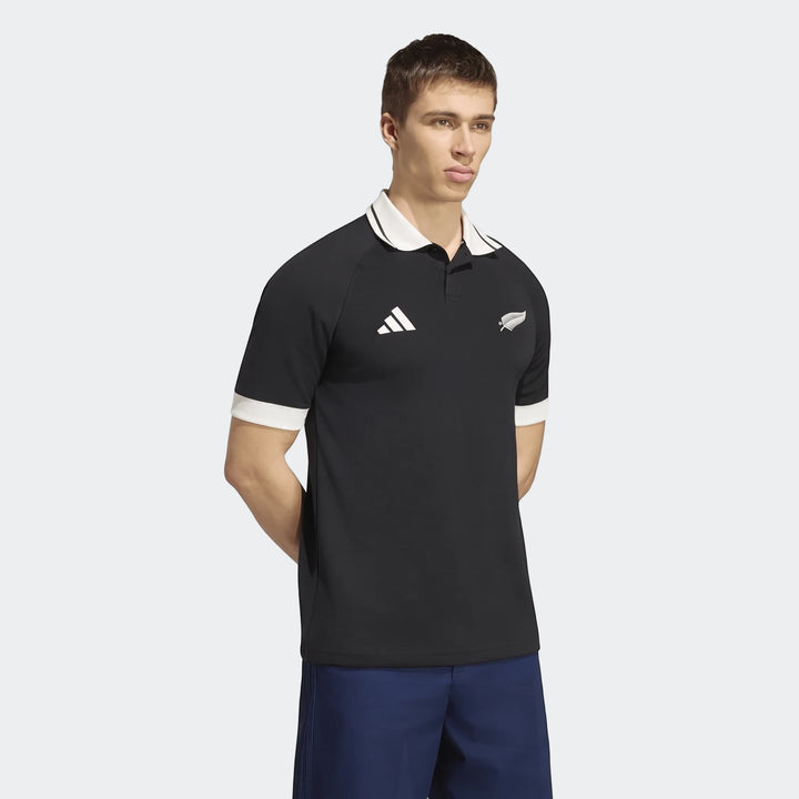 Male model wearing a black New Zealand Rugby Leisurewear Polo Shirt with white collar and cuffs, featuring the Adidas logo