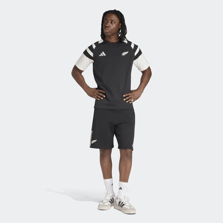 Men's New Zealand Rugby Leisurewear T-Shirt in black and off-white, paired with black shorts and white sneakers, worn by a