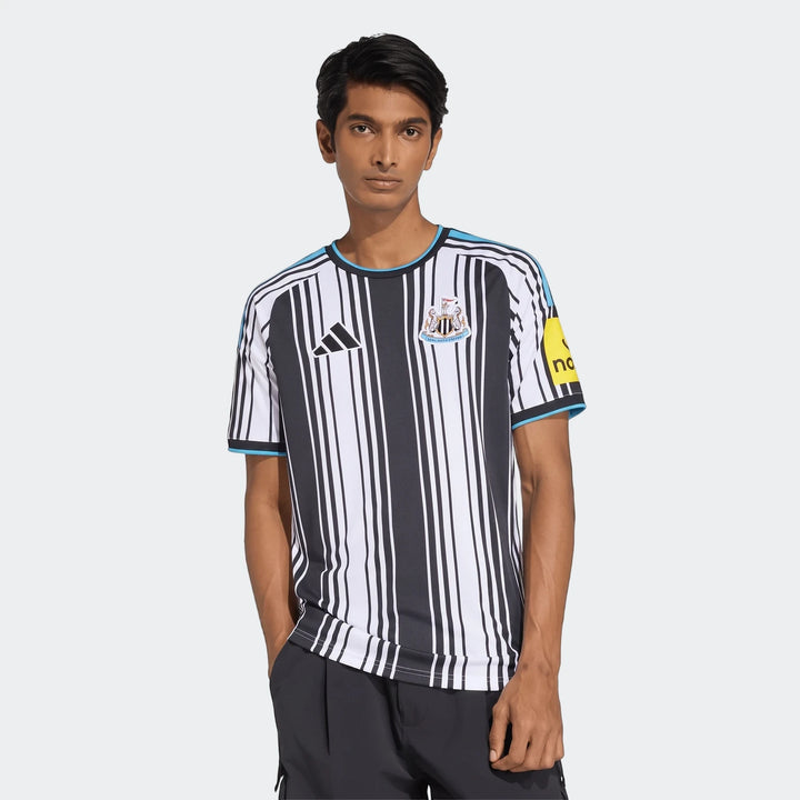 Male model showcasing the Newcastle United FC 26/27 Home Jersey, featuring black and white vertical stripes and blue details.
