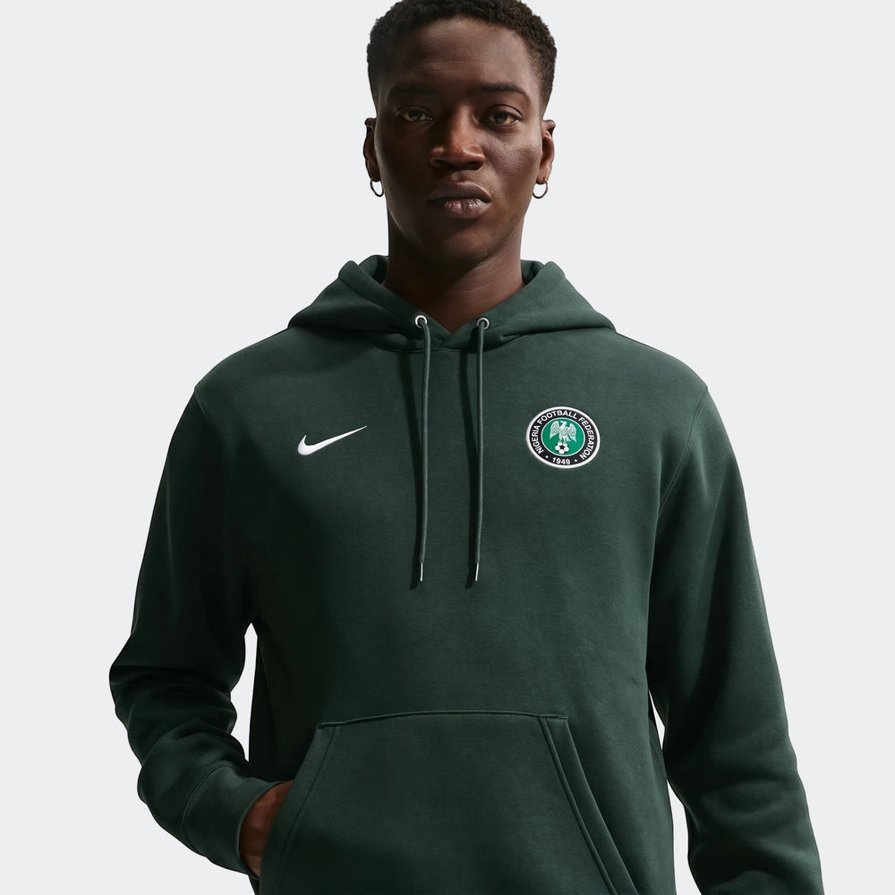 Front view of a man wearing a dark green Nike Nigeria Club men's soccer pullover hoodie with white Nike swoosh and