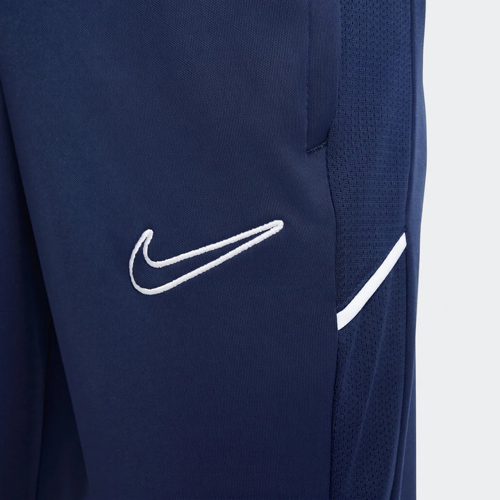 Close-up of Nike Academy Big Kids' Dri-Fit soccer pants in dark blue, featuring a white Nike swoosh logo and side stripe on