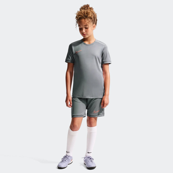Nike Academy Big Kids' Dri-Fit short-sleeve soccer top in gray, worn by a child with matching shorts and cleats.