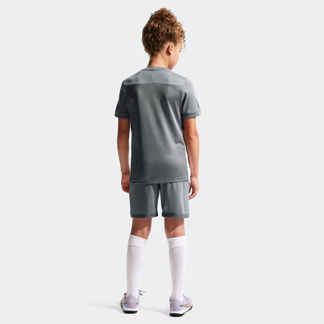 Big Kids' grey Nike Academy Dri-Fit short-sleeve soccer top and matching shorts, worn by a child from the back.
