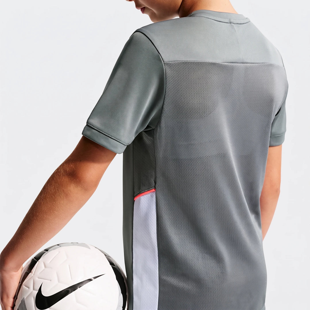 Nike Academy Big Kids' Dri-Fit short sleeve soccer top in grey, worn by a child from the back, holding a soccer ball.