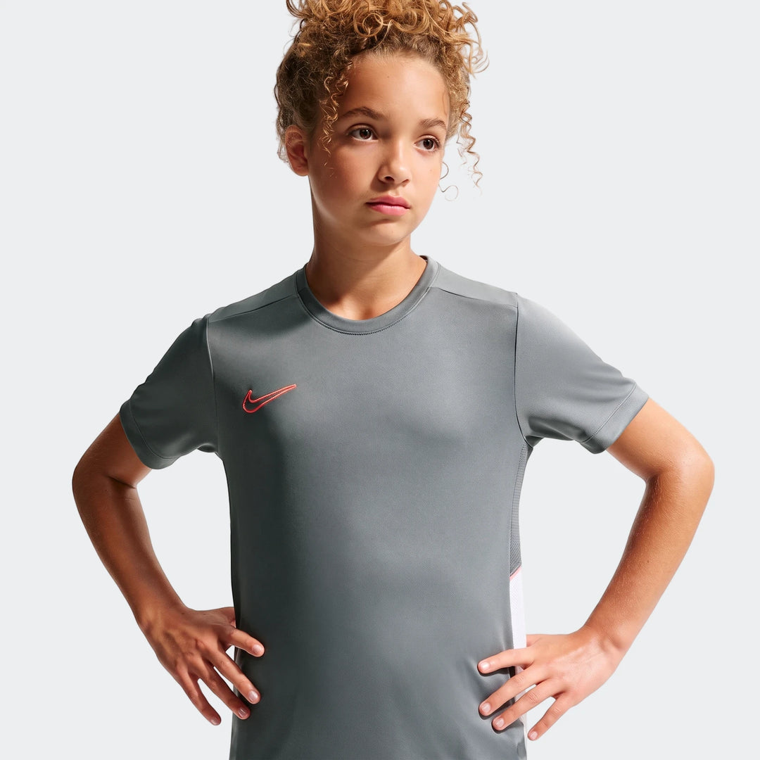 Nike Academy Big Kids' Dri-Fit Soccer Top in grey, worn by a curly-haired child model with hands on hips.