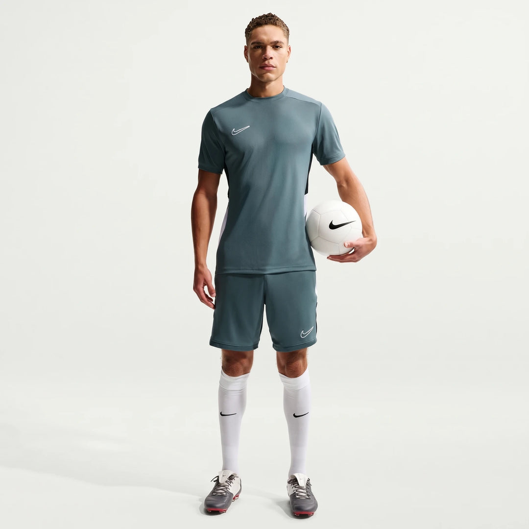 Full body shot of a male model wearing a Nike Academy Green Men's Dri-Fit Short-Sleeve Soccer Top, matching shorts, and