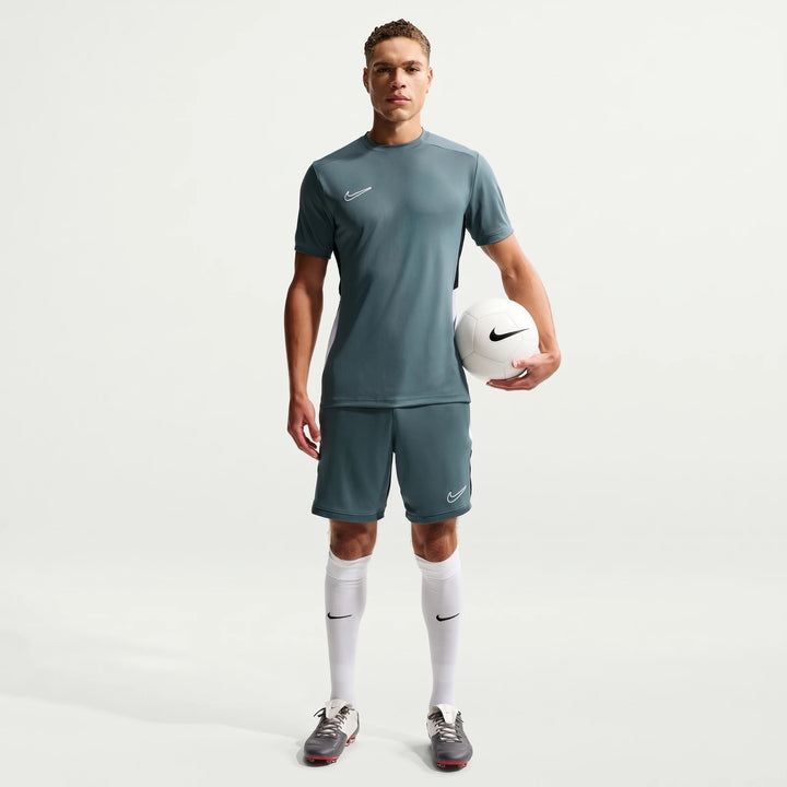 Full body shot of a male model wearing a Nike Academy Green Men's Dri-Fit Short-Sleeve Soccer Top, matching shorts, and