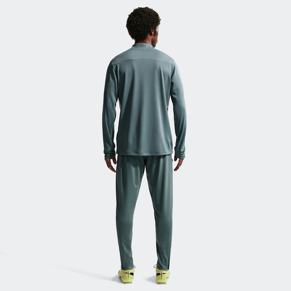 Men's Nike Academy Dri-Fit soccer drill top and matching pants in green, full body view from the back in a studio setting.