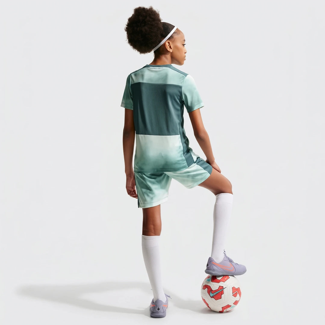 Young girl wearing Nike Academy+ Green Big Kids' Dri-Fit Short-Sleeve Soccer Top and matching shorts, seen from the back