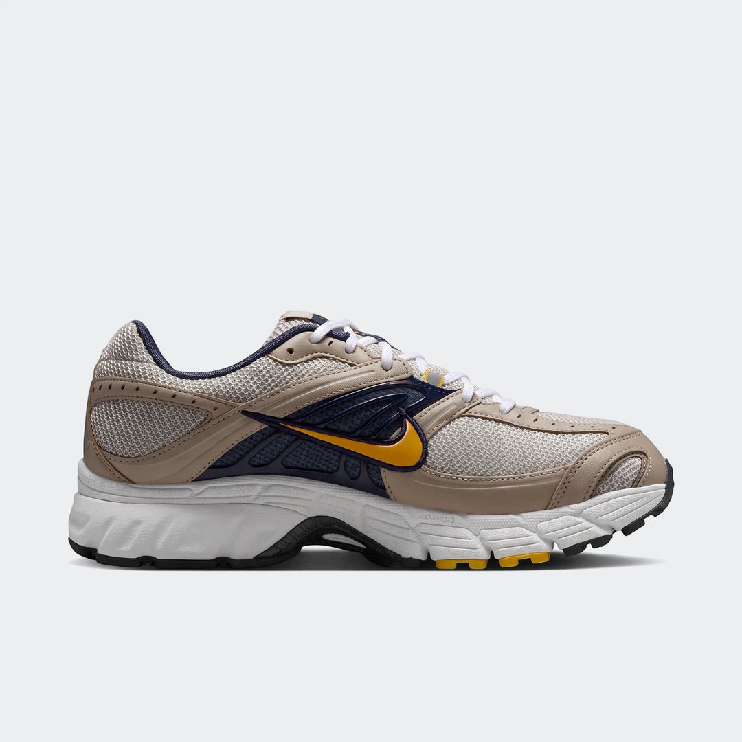 Nike Air Max Moto 2K 2Tone Men's Shoes in beige, navy, and yellow, captured in a dynamic side view.