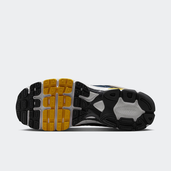 Bottom sole view of a Nike Air Max Moto 2K 2Tone Men's shoe, featuring a black, white, and yellow textured rubber outsole.