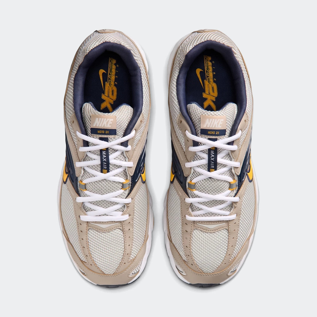Top-down view of Nike Air Max Moto 2K 2Tone men's shoes in light beige, navy, and yellow, showcasing mesh and synthetic