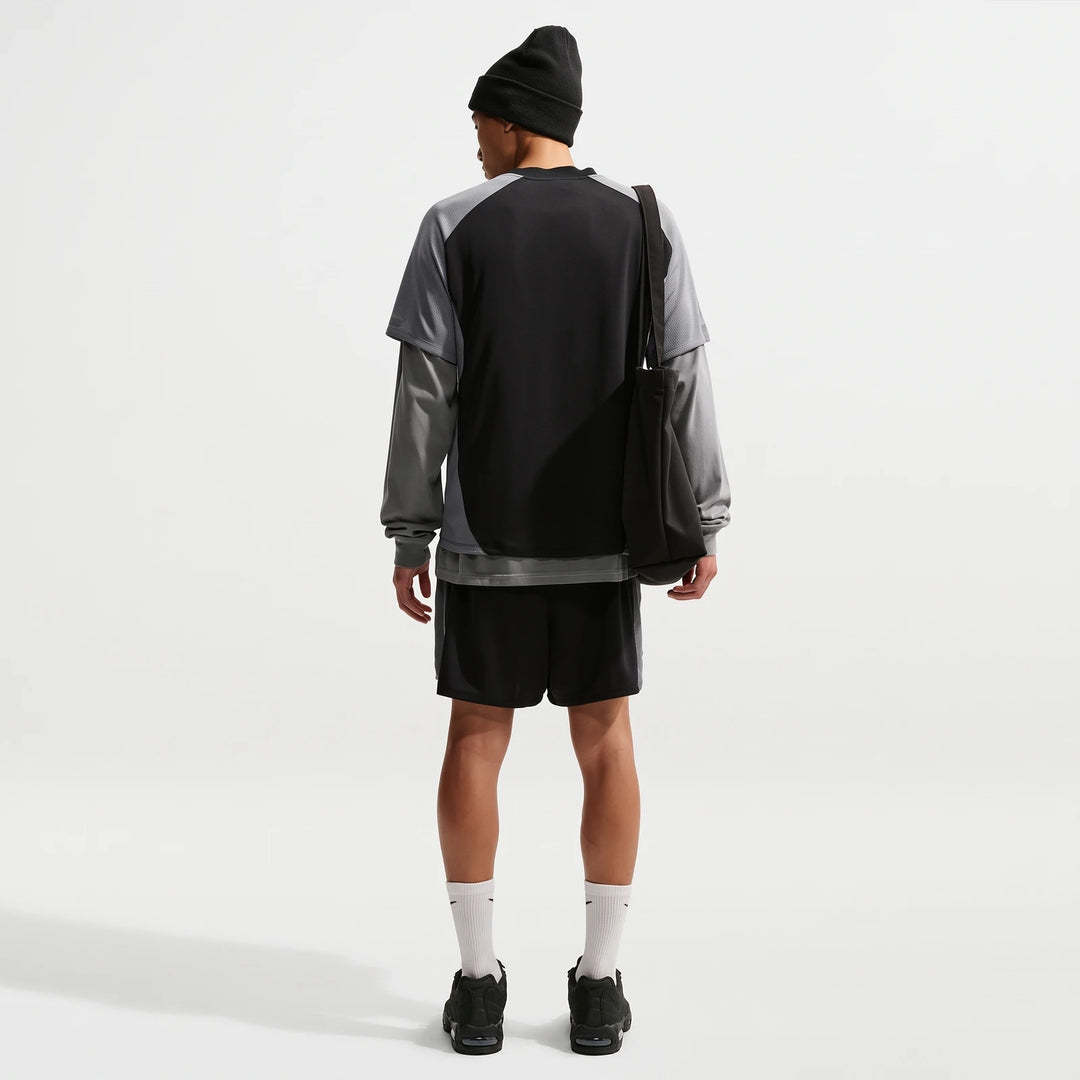 Nike Air Men's Top in black and grey, layered, styled with shorts and a beanie, viewed from the back.