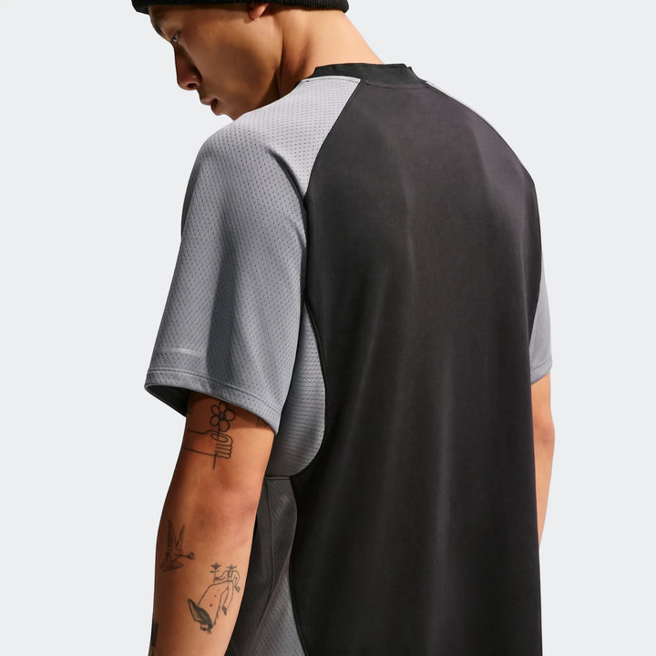 Back view of a man wearing a Nike Air Men's Top in grey and black mesh fabric, showcasing its athletic design.